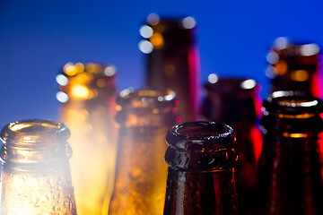 Image showing Neon colored beer bottles. Close up on bright studio background