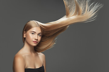 Image showing Beautiful model with long smooth, flying blonde hair isolated on dark studio background.