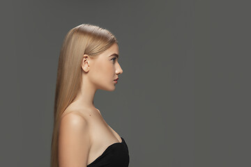 Image showing Beautiful model with long smooth, flying blonde hair isolated on dark studio background.