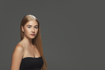 Image showing Beautiful model with long smooth, flying blonde hair isolated on dark studio background.