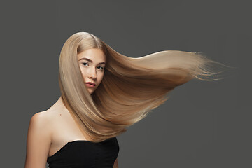 Image showing Beautiful model with long smooth, flying blonde hair isolated on dark studio background.