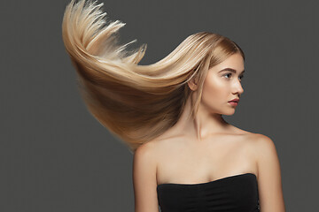 Image showing Beautiful model with long smooth, flying blonde hair isolated on dark studio background.