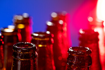 Image showing Neon colored beer bottles. Close up on bright studio background