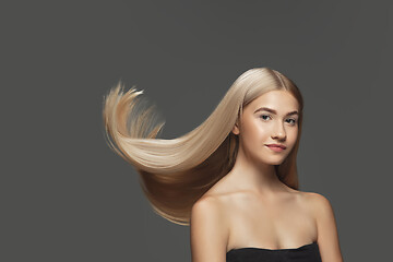 Image showing Beautiful model with long smooth, flying blonde hair isolated on dark studio background.