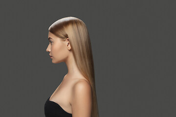 Image showing Beautiful model with long smooth, flying blonde hair isolated on dark studio background.