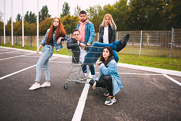 Image showing Group of four young diverse friends in jeanse outfit look carefree, young and happy on city\'s streets