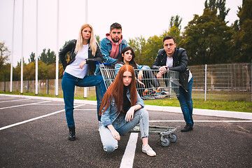 Image showing Group of four young diverse friends in jeanse outfit look carefree, young and happy on city\'s streets