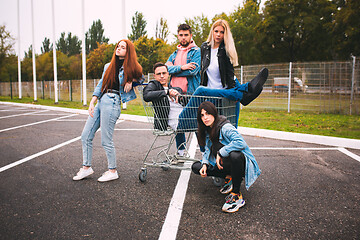 Image showing Group of four young diverse friends in jeanse outfit look carefree, young and happy on city\'s streets