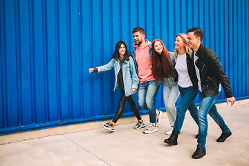 Image showing Group of four young diverse friends in jeanse outfit look carefree, young and happy on city\'s streets