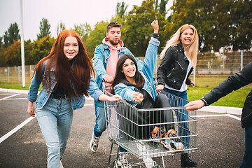 Image showing Group of four young diverse friends in jeanse outfit look carefree, young and happy on city\'s streets