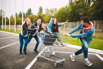 Image showing Group of four young diverse friends in jeanse outfit look carefree, young and happy on city\'s streets