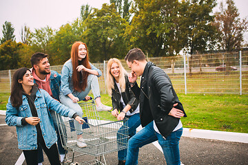 Image showing Group of four young diverse friends in jeanse outfit look carefree, young and happy on city\'s streets