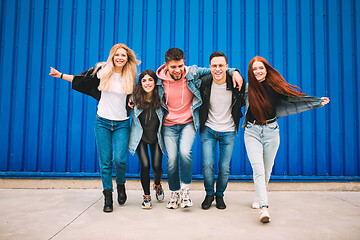 Image showing Group of four young diverse friends in jeanse outfit look carefree, young and happy on city\'s streets