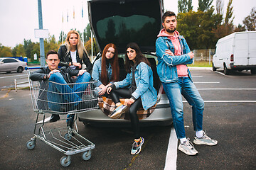 Image showing Group of four young diverse friends in jeanse outfit look carefree, young and happy on city\'s streets