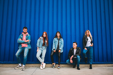 Image showing Group of four young diverse friends in jeanse outfit look carefree, young and happy on city\'s streets