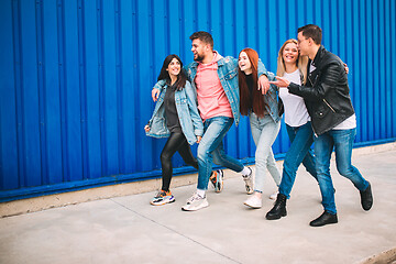 Image showing Group of four young diverse friends in jeanse outfit look carefree, young and happy on city\'s streets