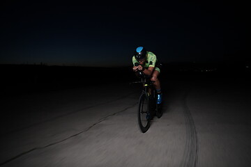 Image showing triathlon athlete riding bike fast at night