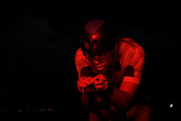 Image showing triathlon athlete riding bike fast at night