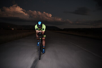 Image showing triathlon athlete riding bike fast at night