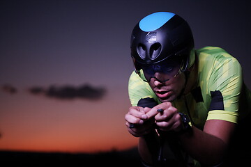 Image showing triathlon athlete riding bike fast at night