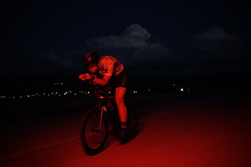 Image showing triathlon athlete riding bike fast at night