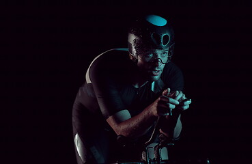 Image showing triathlon athlete riding bike fast at night