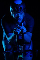 Image showing triathlon athlete riding bike fast at night