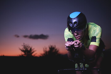 Image showing triathlon athlete riding bike fast at night