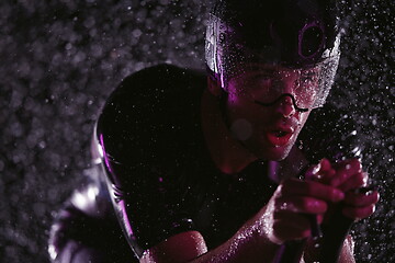 Image showing triathlon athlete riding bike fast on rainy night