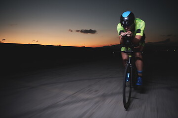 Image showing triathlon athlete riding bike fast at night