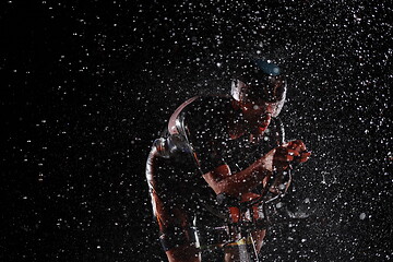 Image showing triathlon athlete riding bike fast on rainy night