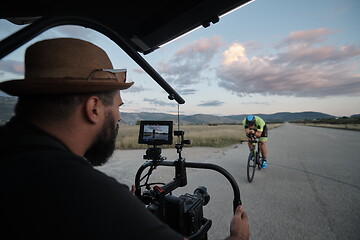 Image showing videographer taking action shot of triathlon athlete while riding bike