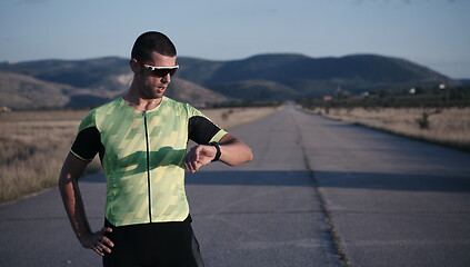 Image showing triathlon athlete resting and setting smartwatch