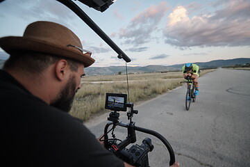 Image showing videographer taking action shot of triathlon athlete while riding bike