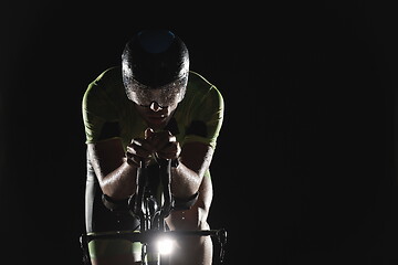 Image showing triathlon athlete riding bike fast at night