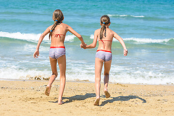 Image showing Two little sisters running to swim in the sea, back visas