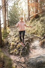 Image showing Active sporty woman listening to the music while running in autumn fall forest. Female runner training outdoor. Healthy lifestyle image of young caucasian woman jogging outside