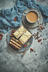 Image showing Tasty layered cake sprinkled with white chocolate. Served with cup of coffee on a gray concrete