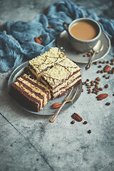 Image showing Homemade layered cake sprinkled with white chocolate. Served with cup of coffee on a gray concrete