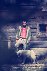 Image showing hipster with dog in front of wooden house