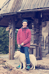 Image showing young hipster with dog in front of wooden house