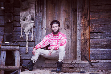 Image showing portrait of young hipster in front of wooden house