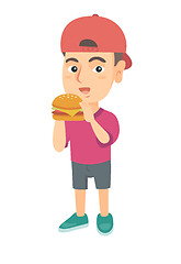 Image showing Little caucasian boy eating a hamburger.