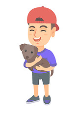 Image showing Caucasian happy boy in a cap holding a dog.