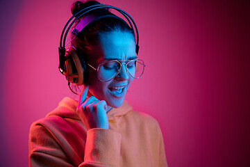 Image showing Fashion pretty woman with headphones listening to music over neon background