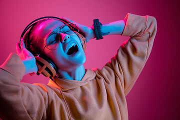 Image showing Fashion pretty woman with headphones listening to music over neon background