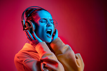 Image showing Fashion pretty woman with headphones listening to music over neon background