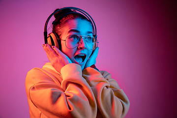 Image showing Fashion pretty woman with headphones listening to music over neon background