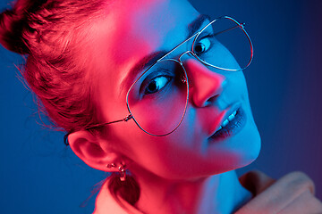 Image showing Fashion pretty woman with headphones listening to music over neon background