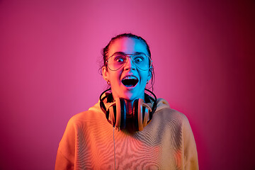 Image showing Fashion pretty woman with headphones listening to music over neon background